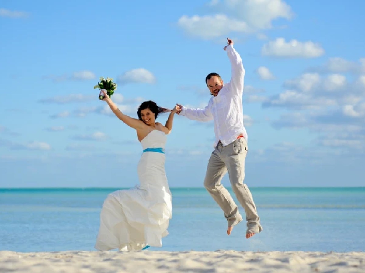 Bride and groom jumping on the beach