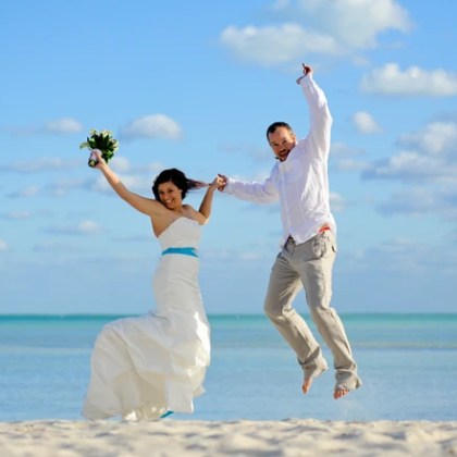Bride and groom jumping on the beach